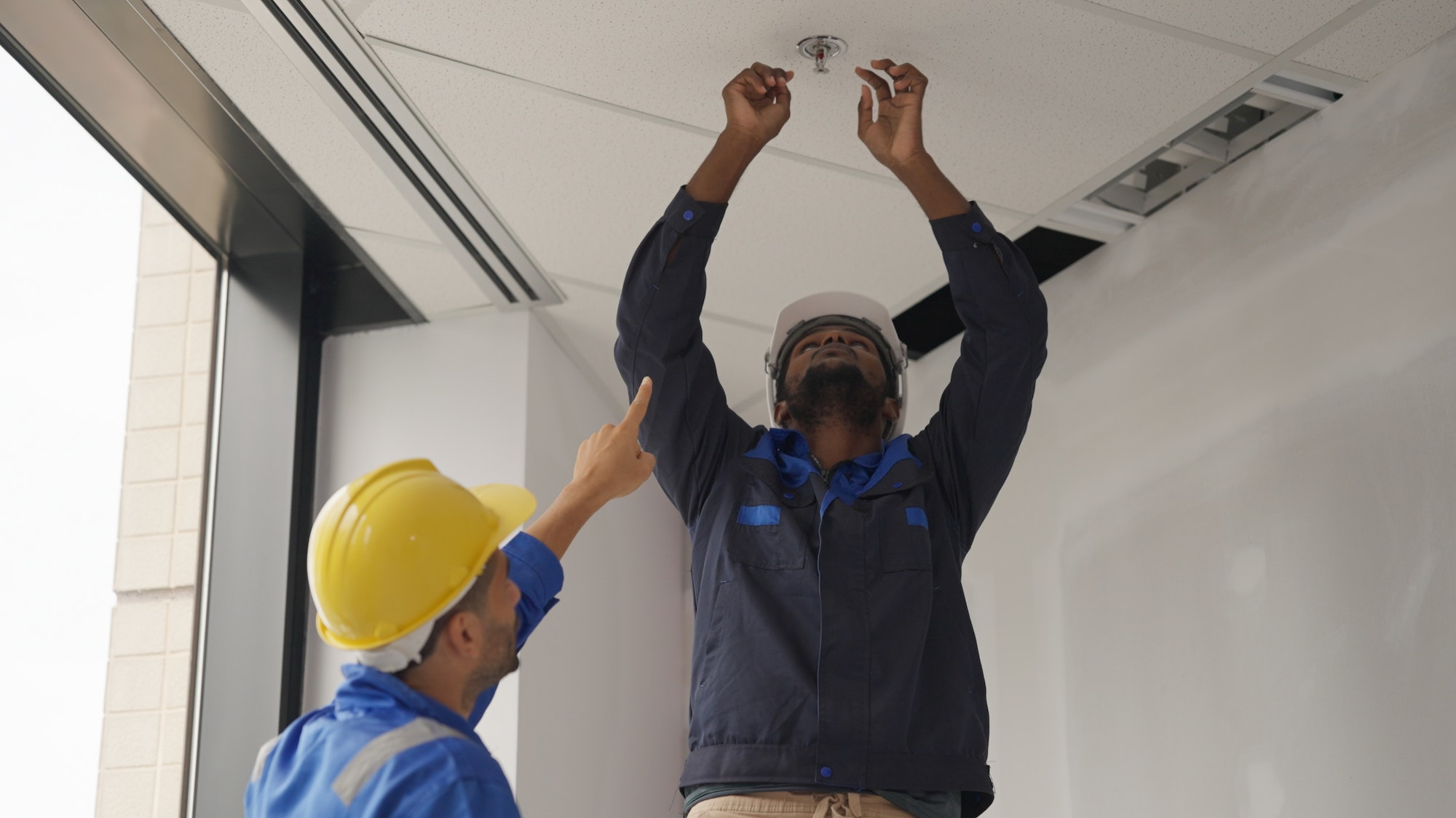 Engineers team installing fire sprinkler in office at building site