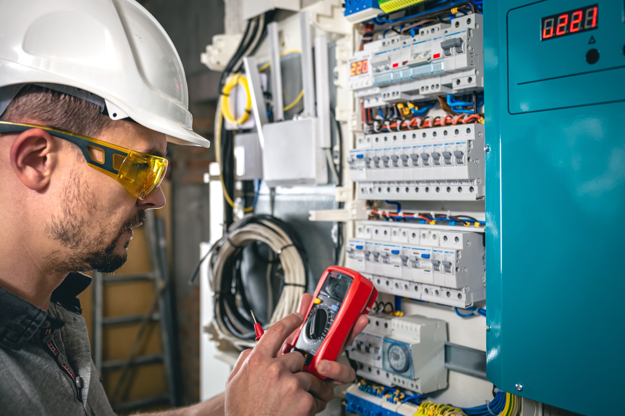 Man, an electrical technician working in a switchboard with fuses.