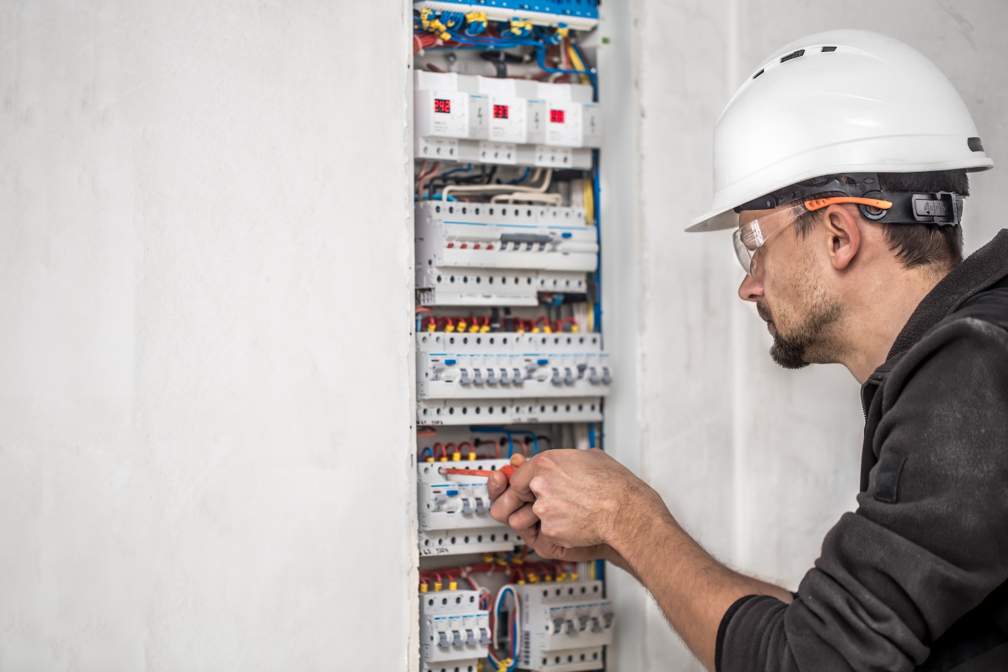 Man, an electrical technician working in a switchboard with fuses.