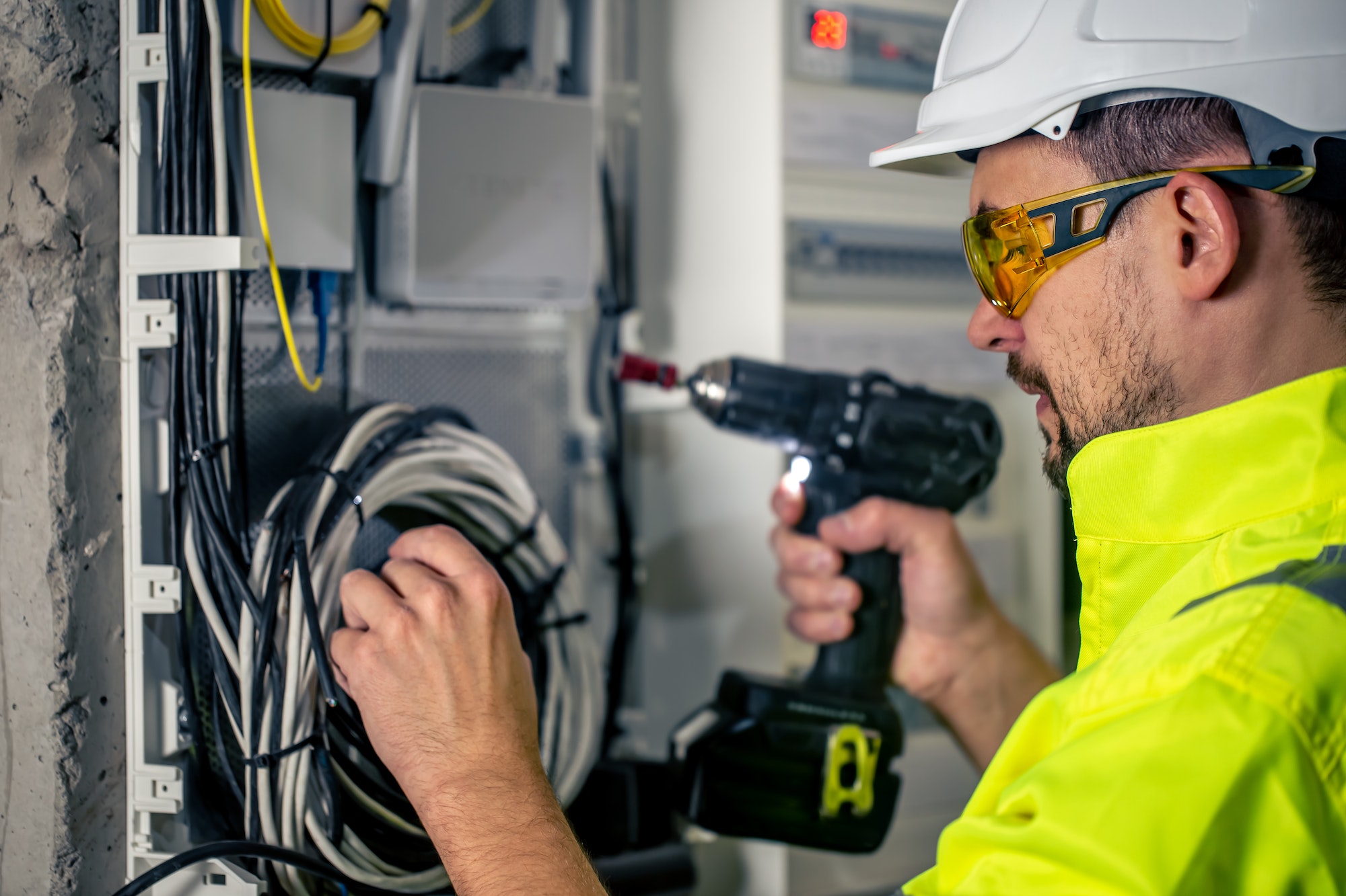 Man, an electrical technician working in a switchboard with fuses.