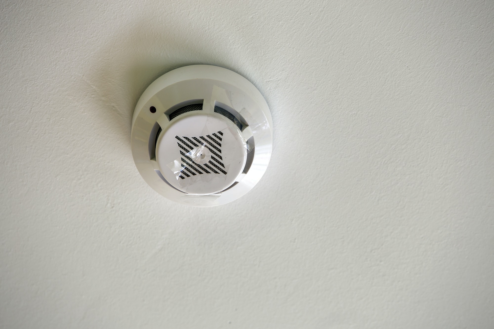 Smoke detector of fire alarm device on copy space background of white ceiling